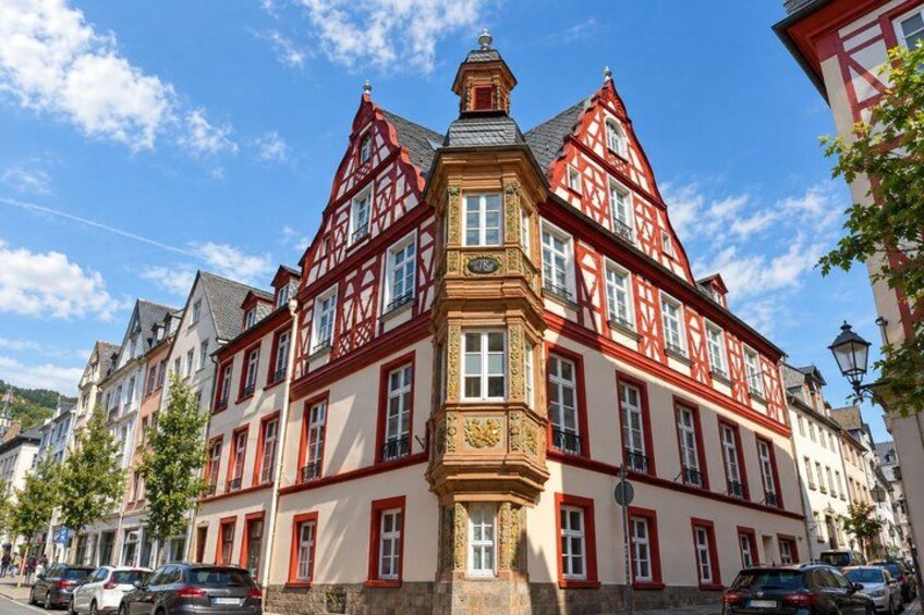 A traditional half-timbered building with red and white facades, a prominent corner tower, and a clear blue sky. 3