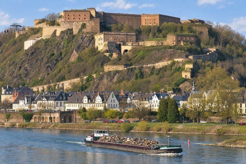 A river with a boat, a castle on a hill, and houses along the riverbank. 4