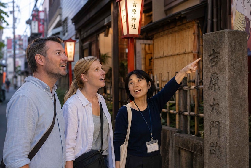 Tres personas observando un monumento de piedra con caracteres japoneses. 1