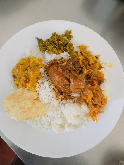 A plate of food with white rice, a piece of meat, a yellow dish, and a green vegetable. 3