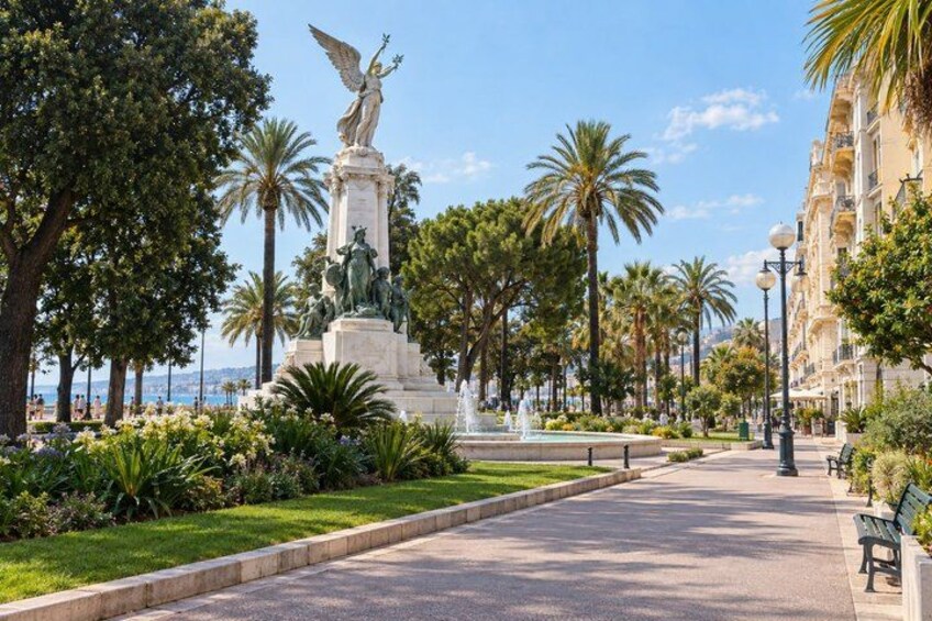 A park with a statue, palm trees, benches, and a fountain. 5