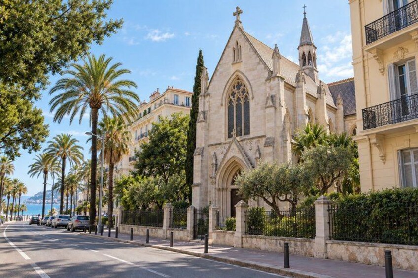 A street with a historic church, palm trees, and a coastal view. 4