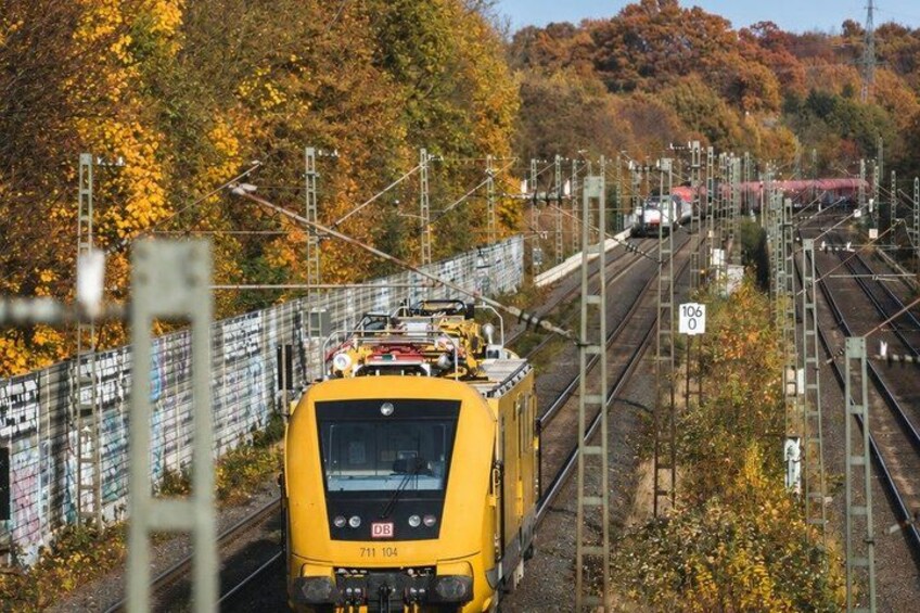 A yellow train on tracks with a speed limit sign of 106. 5