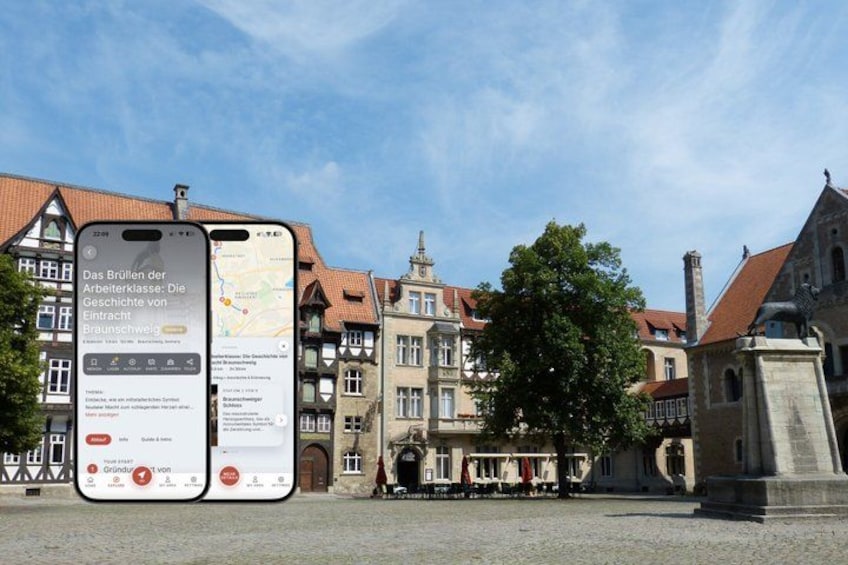 A smartphone displaying a map with text in German, a cobblestone square, historic buildings, and a statue. 1