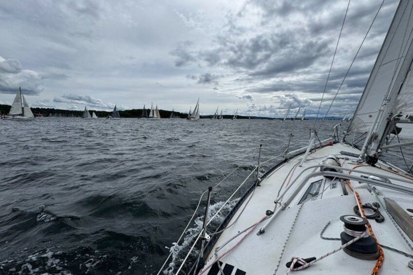A sailboat on the water with other sailboats in the distance. 1