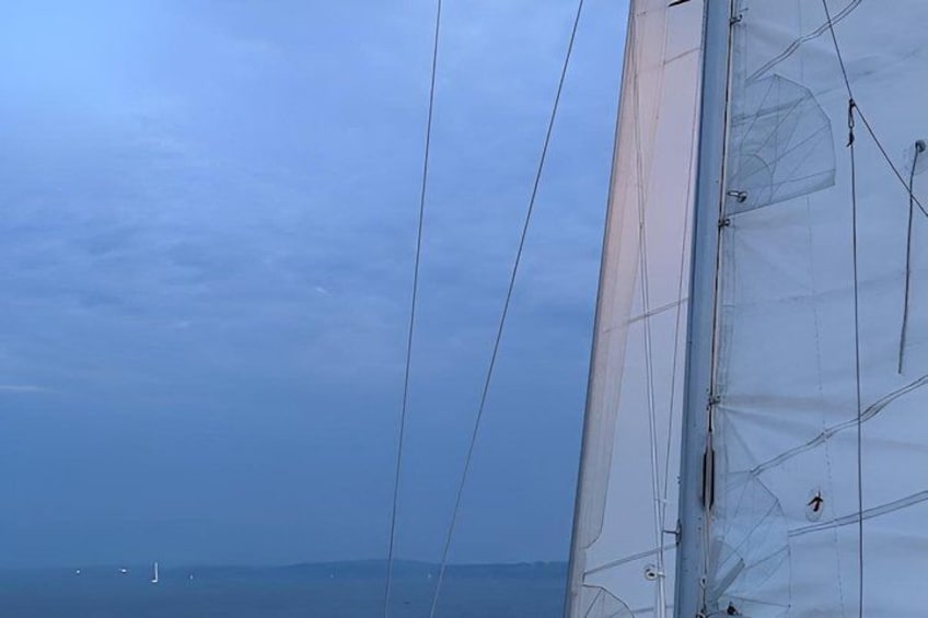 A sailboat with a clear sky and distant land. 4
