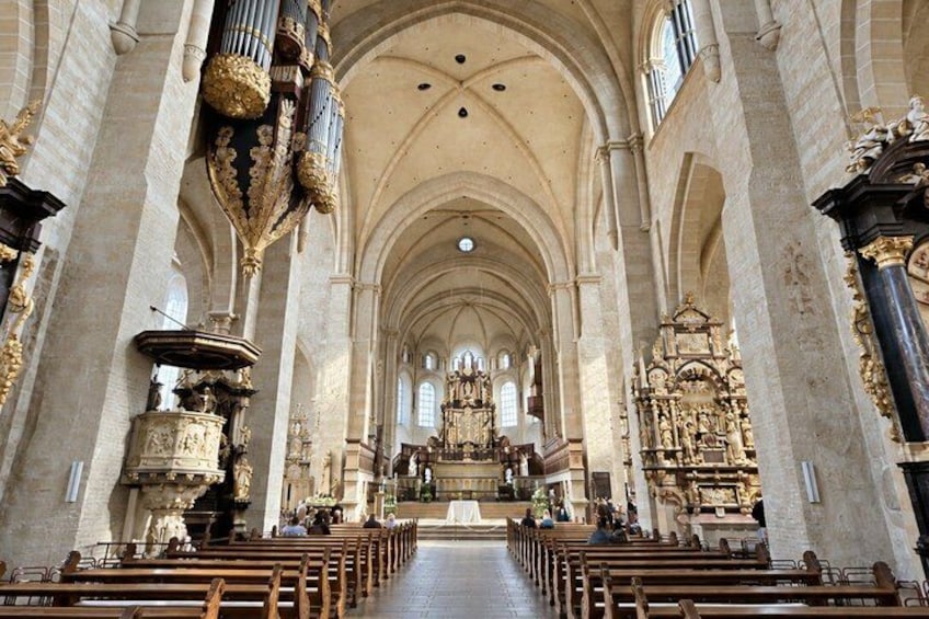 A cathedral interior with high vaulted ceilings, rows of pews, and ornate religious statues and altars. 2