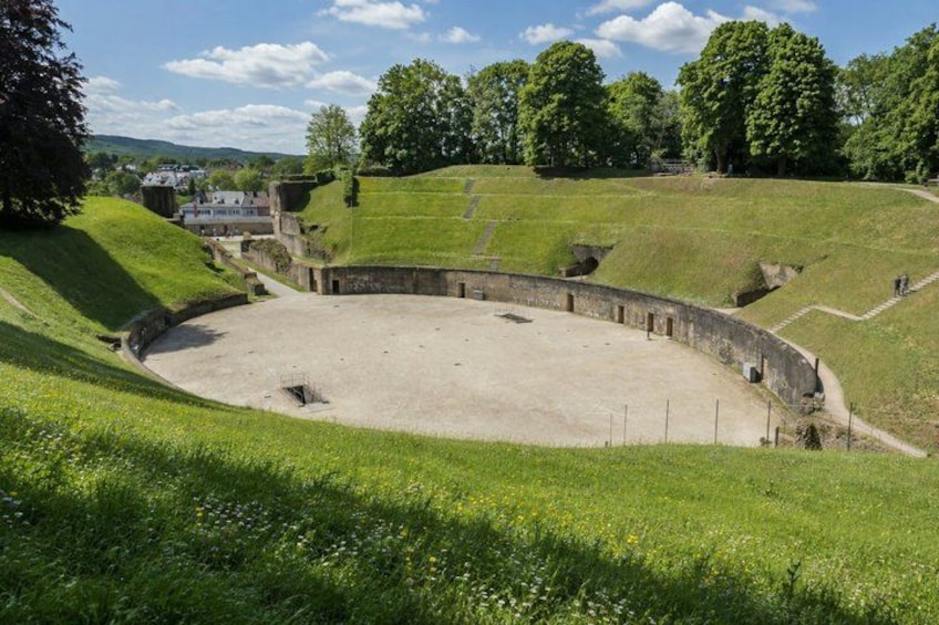 A historical amphitheater with a stone stage and tiered seating. 3