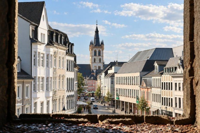 A street with historic buildings, a church tower, and cobblestone pavement. 4