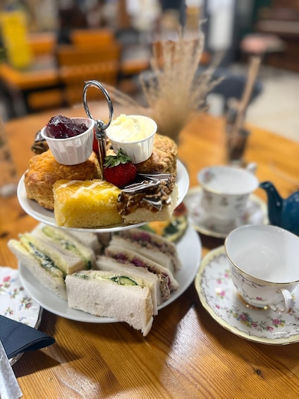 A tiered dessert tray with various pastries and a cup of tea. 1