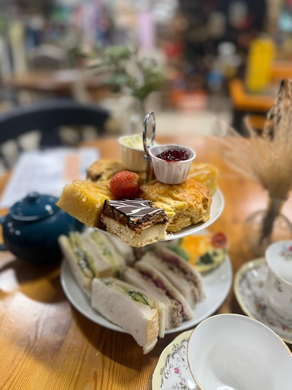 A plate of sandwiches and a dessert with a strawberry and jam. 4