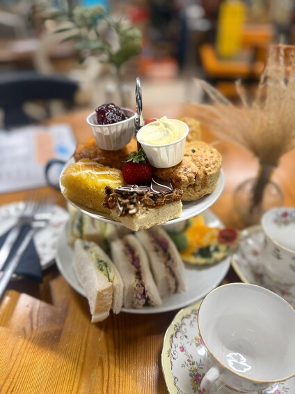 A three-tiered dessert stand with various pastries and a cup of tea. 3
