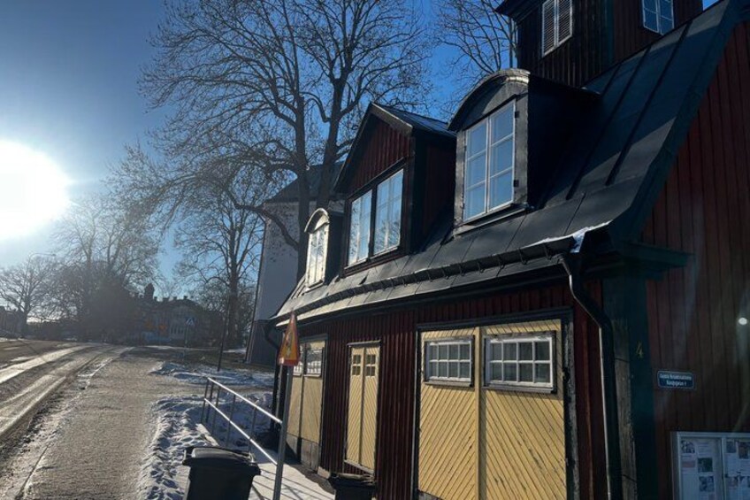 A wooden building with a black roof, a yellow wall, and a window. 4