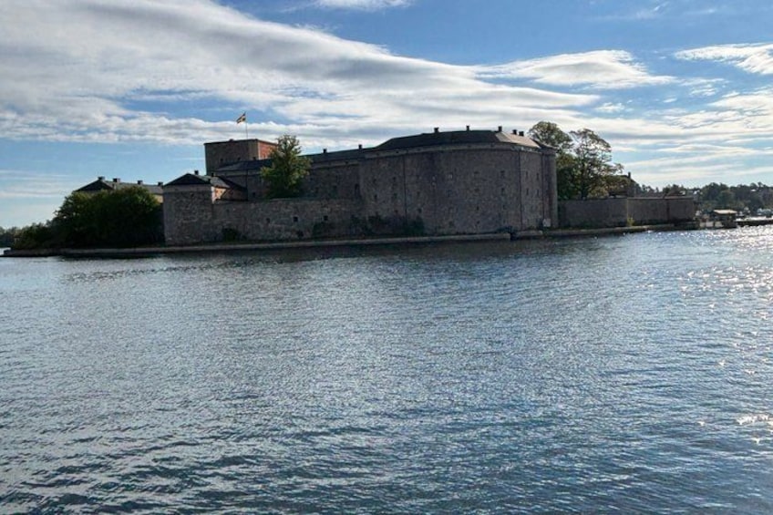 A large stone fortress by a calm body of water. 1