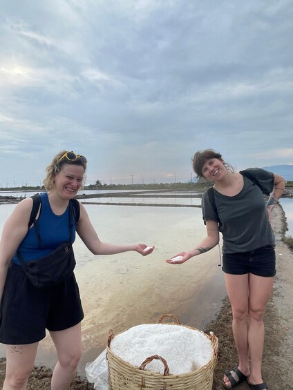 Two people standing by a body of water with a basket of white material in the foreground. 4