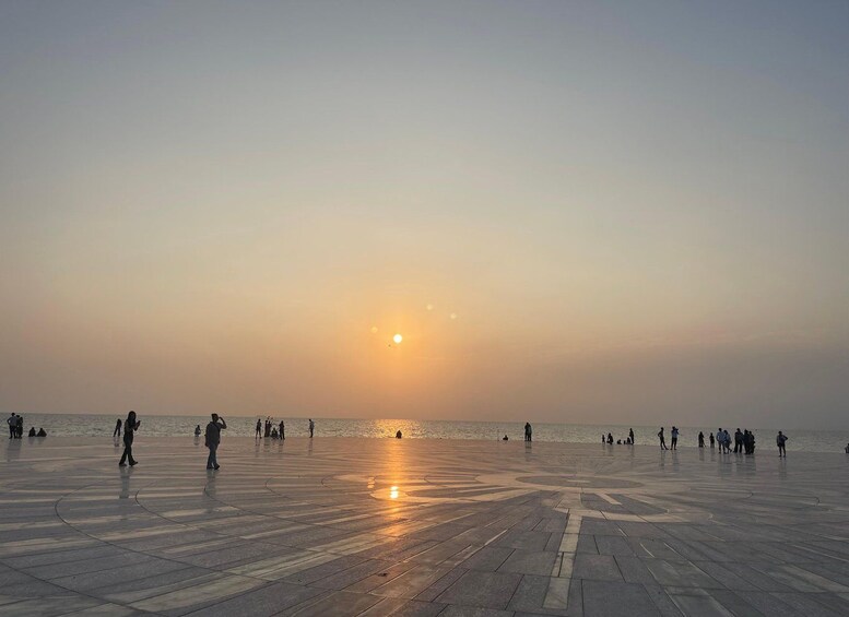 A sunset over a waterfront promenade with people walking and sitting. 3