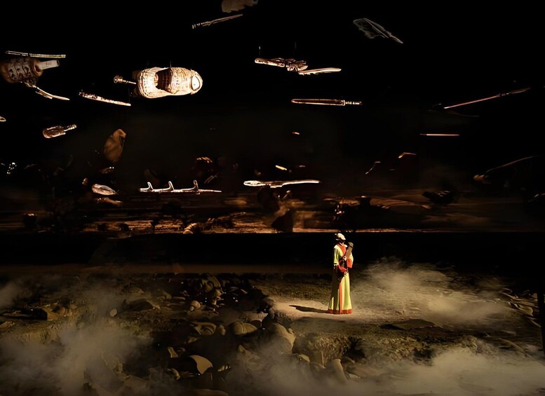 A person in a long dress standing in a misty area with floating objects. 1