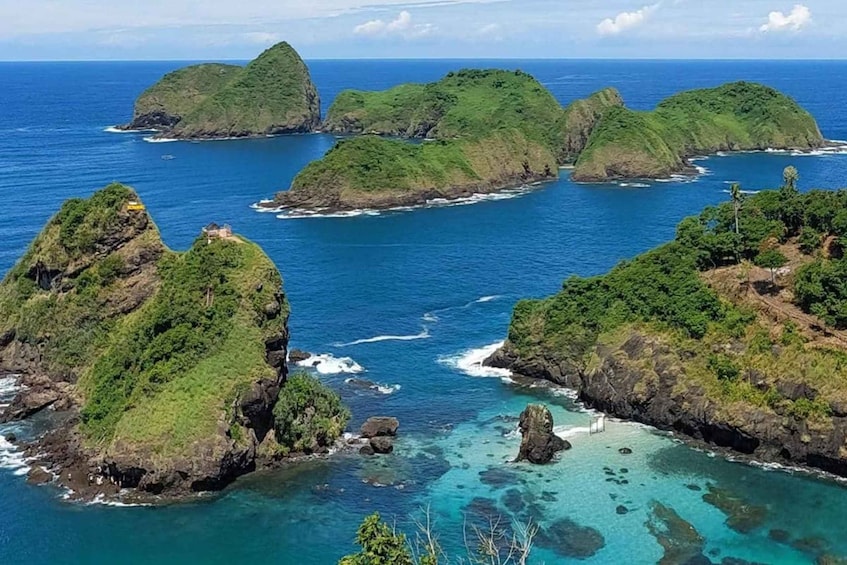 A coastal landscape with multiple green islands surrounded by clear blue waters. 4