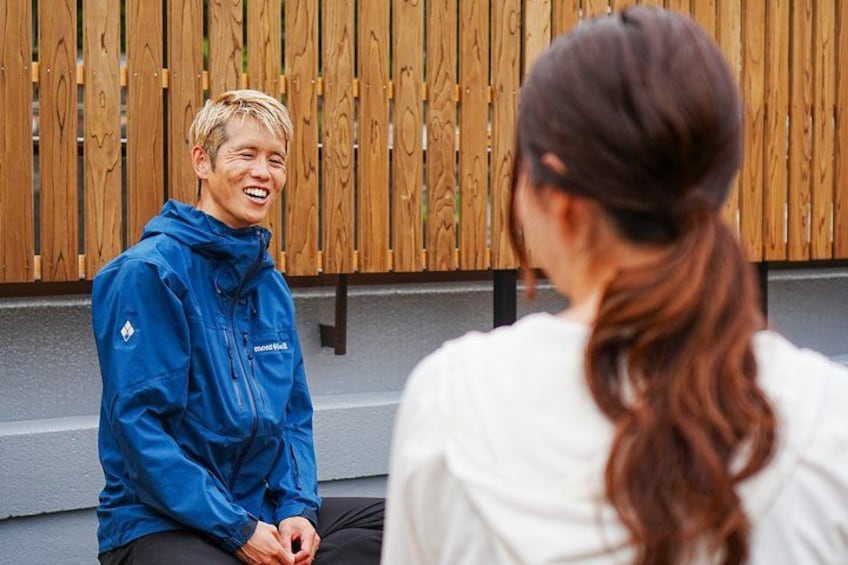 Two people sitting on steps, one in a blue jacket and the other in a white shirt, with a wooden fence in the background. 5