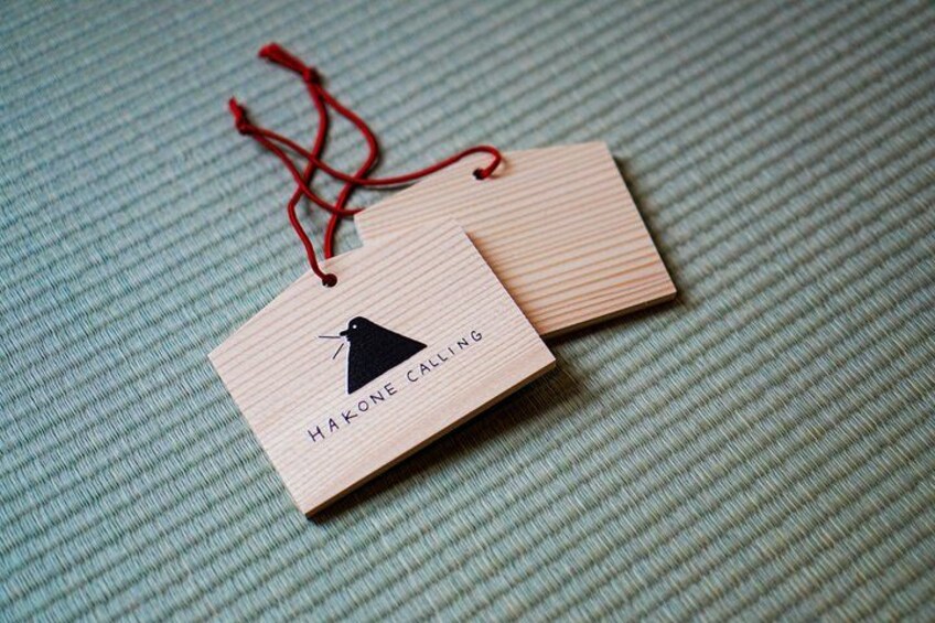 Two wooden tags with a bird illustration and the text 'HAKONE CALLING' on a textured fabric background. 4