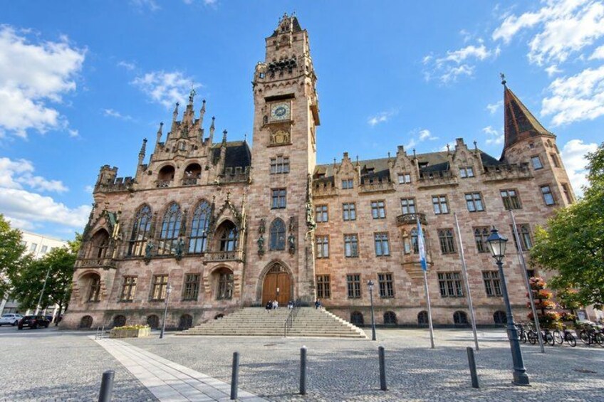 A historic building with a prominent clock tower, arched windows, and a large entrance. 5