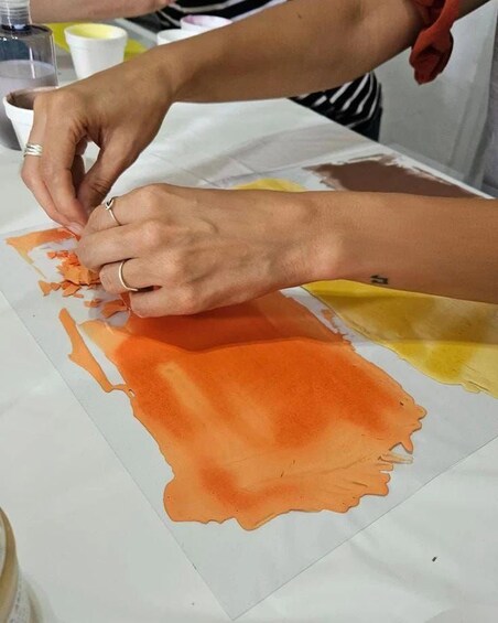 A person applying orange paint to a white surface. 5