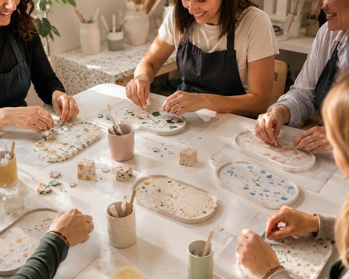 A group of people engaged in a pottery-making activity, with various clay pieces and tools on a table. 4