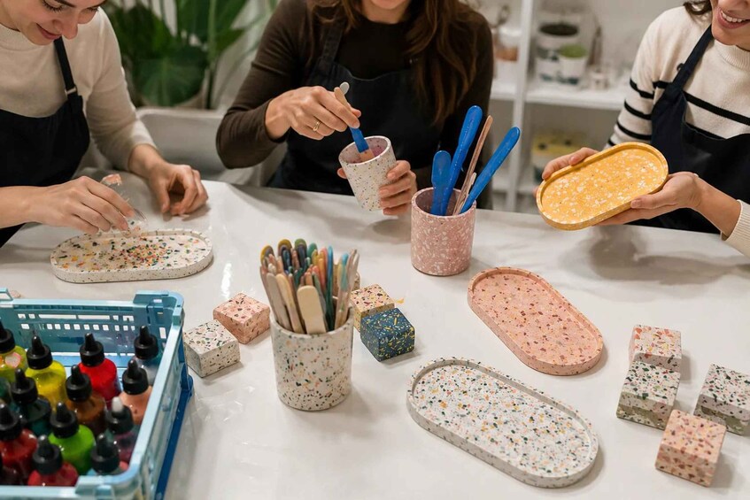 A crafting activity with people working on ceramic tiles, colorful paint bottles, and various crafting tools. 1