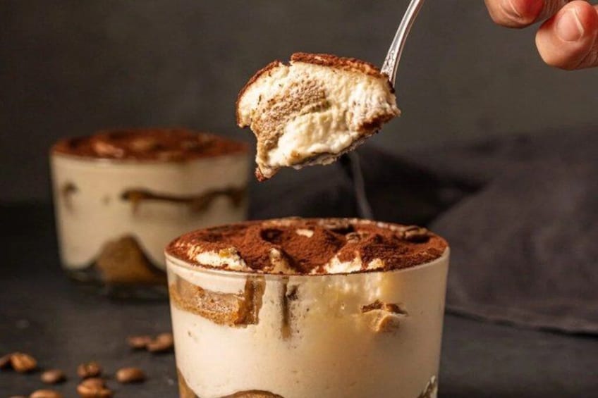 A dessert with layers, a spoon lifting a piece, and a dark background. 3