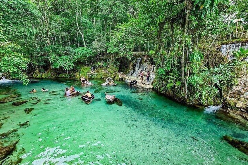 A clear turquoise river surrounded by dense greenery, with people in small boats. 3