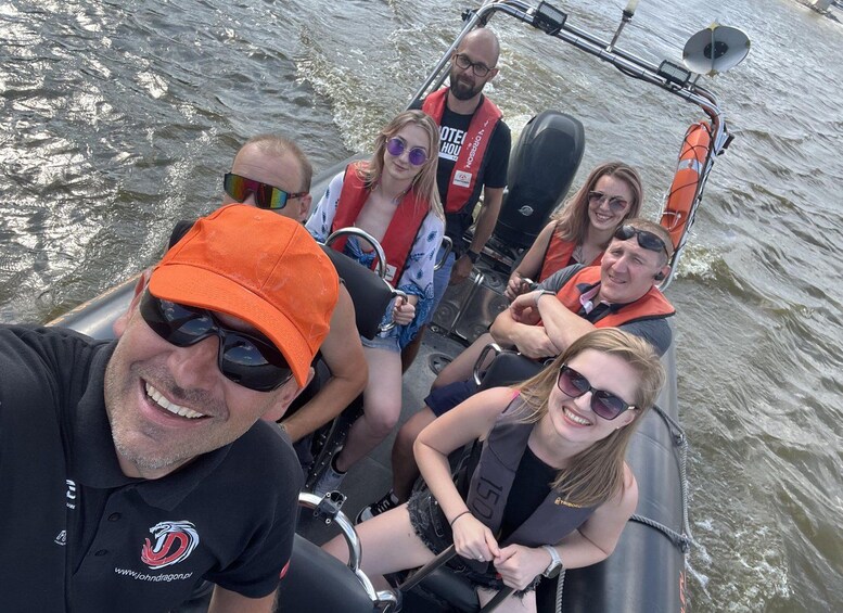 A group of people on a boat with life jackets, one person wearing an orange cap, and a logo on a shirt. 4