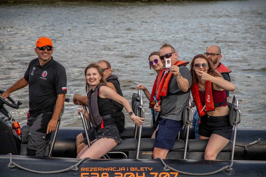 A group of people on a boat, wearing life jackets, with a man steering. 2