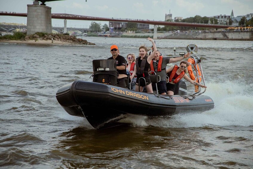 Een groep mensen in een kleine motorboot genaamd 'John Dragon', met reddingboeien en een persoon in een oranje pet. 5
