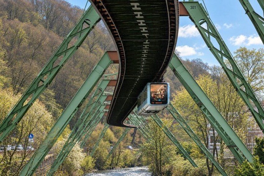A green metal bridge with a river underneath and trees in the background. 4