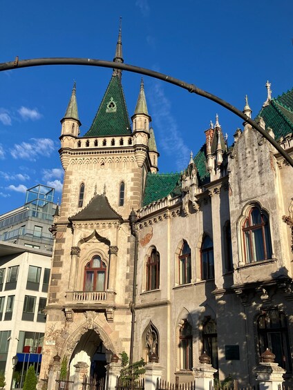A historic building with ornate architecture, including a tower with a green roof and multiple spires. 1