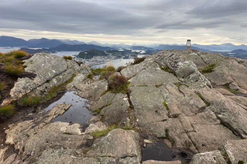 A rocky terrain with a small monument, a lake, and distant mountains. 3