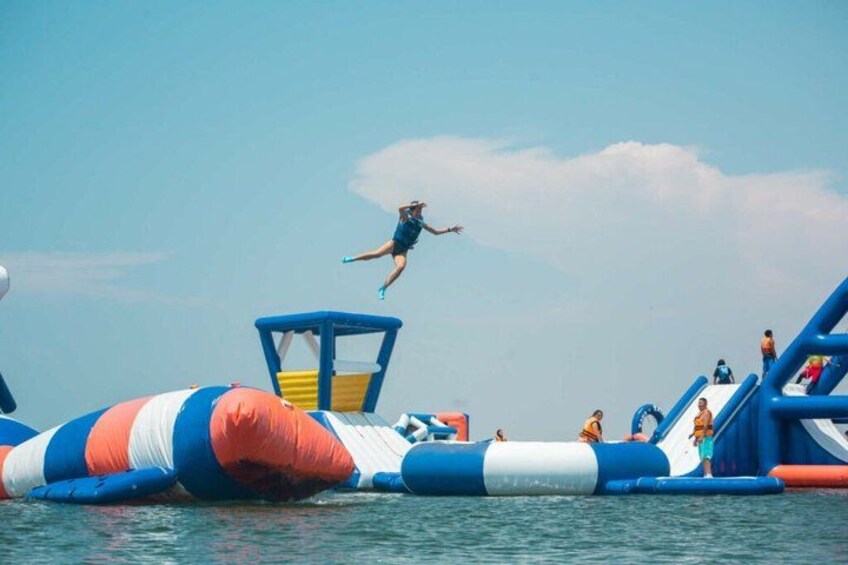 A person jumping off a blue and white inflatable structure into a body of water. 2