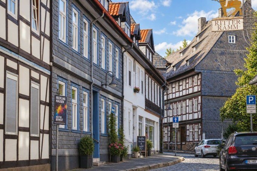A street with traditional half-timbered houses, a parked car, and a sign for a recycling house. 5
