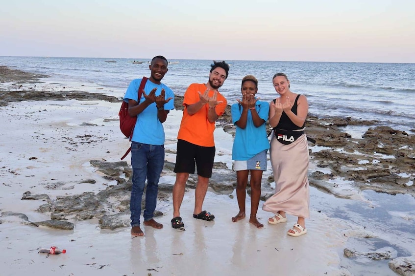 A group of people standing on a rocky beach with the ocean in the background. 3