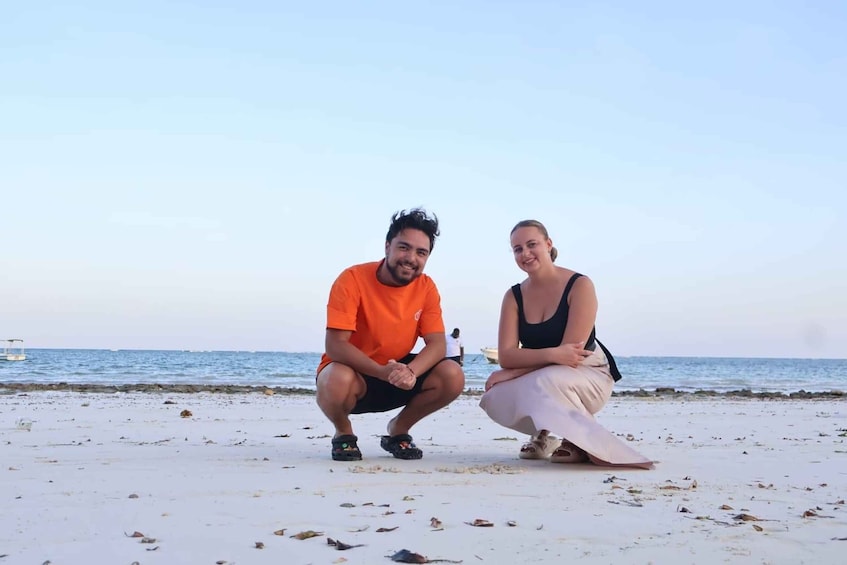Two people sitting on a beach with the ocean in the background. 5
