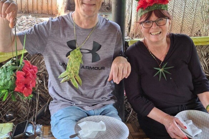 Two people sitting on a bench with a plant and a red flower. 4