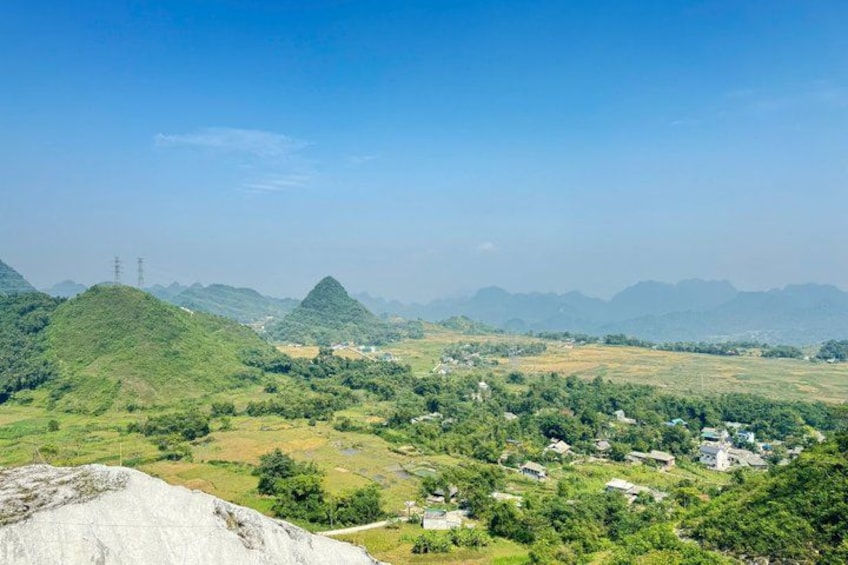 A mountainous landscape with a village, green fields, and power lines. 2