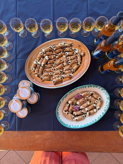 A table with cannoli, wine glasses, and bottles. 2