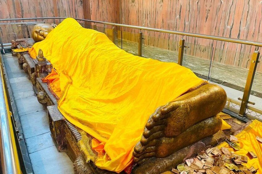 A golden statue covered with a yellow cloth, surrounded by a railing. 5