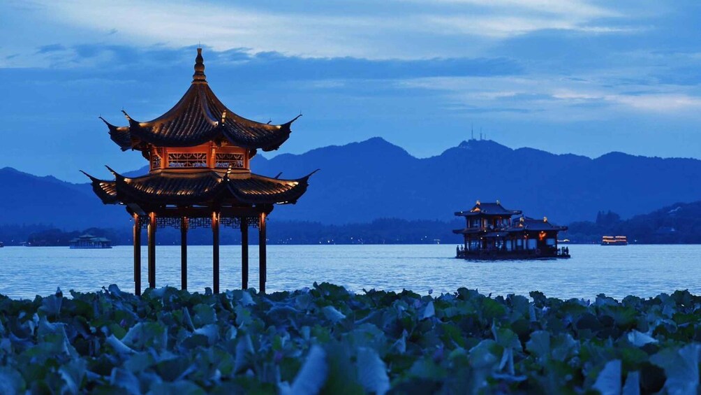 A traditional Chinese pavilion on stilts over water, with mountains in the background. 3
