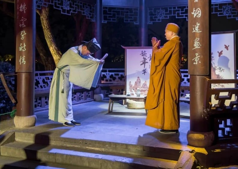 A traditional performance with two actors in historical costumes on a stage with a backdrop of Chinese characters and a traditional setting. 4