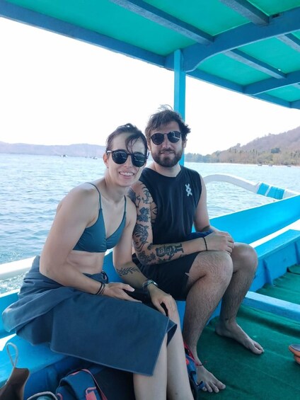 Two people sitting on a boat with a body of water and hills in the background. 5