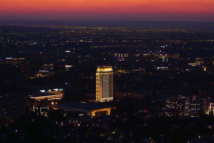 A cityscape at dusk with a prominent illuminated skyscraper in the center. 4