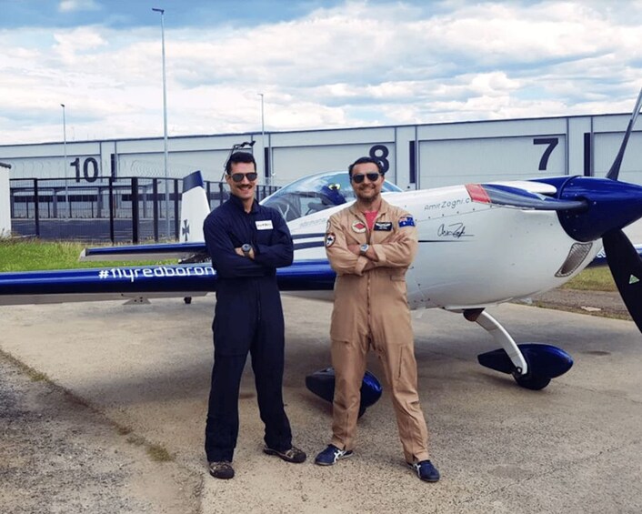 Two people standing in front of an airplane with the number 7 on its side. 2