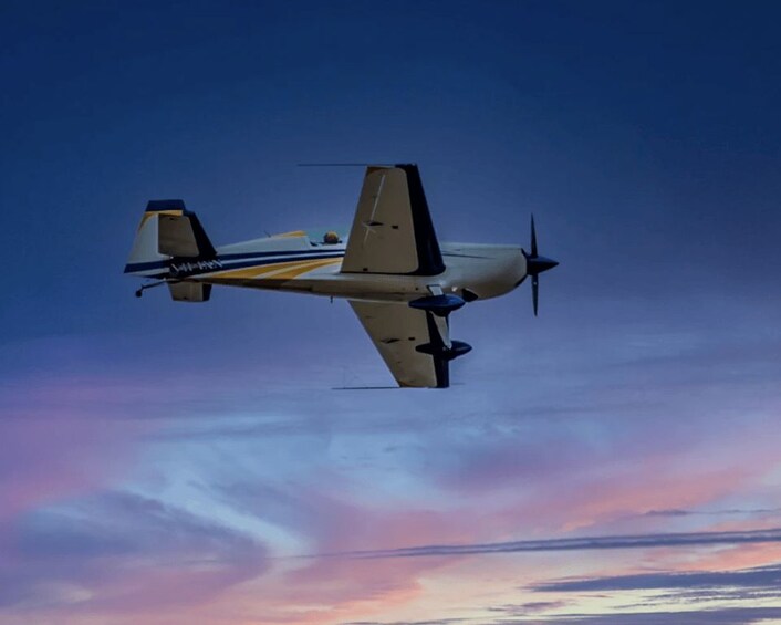 A propeller-driven aircraft flying against a sunset sky. 3